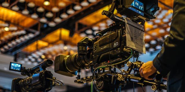 きらびやかなライトの下で構えるTVクルー